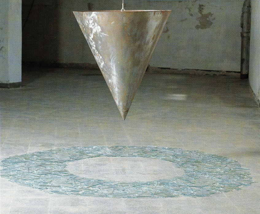 Steel cone over circle of broken glass with engravings