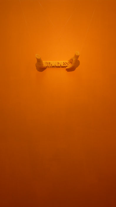 Wachsguss: Zwei orangefarbene Hände halten das Wort 'nothingness' vor orangefarbener Wand